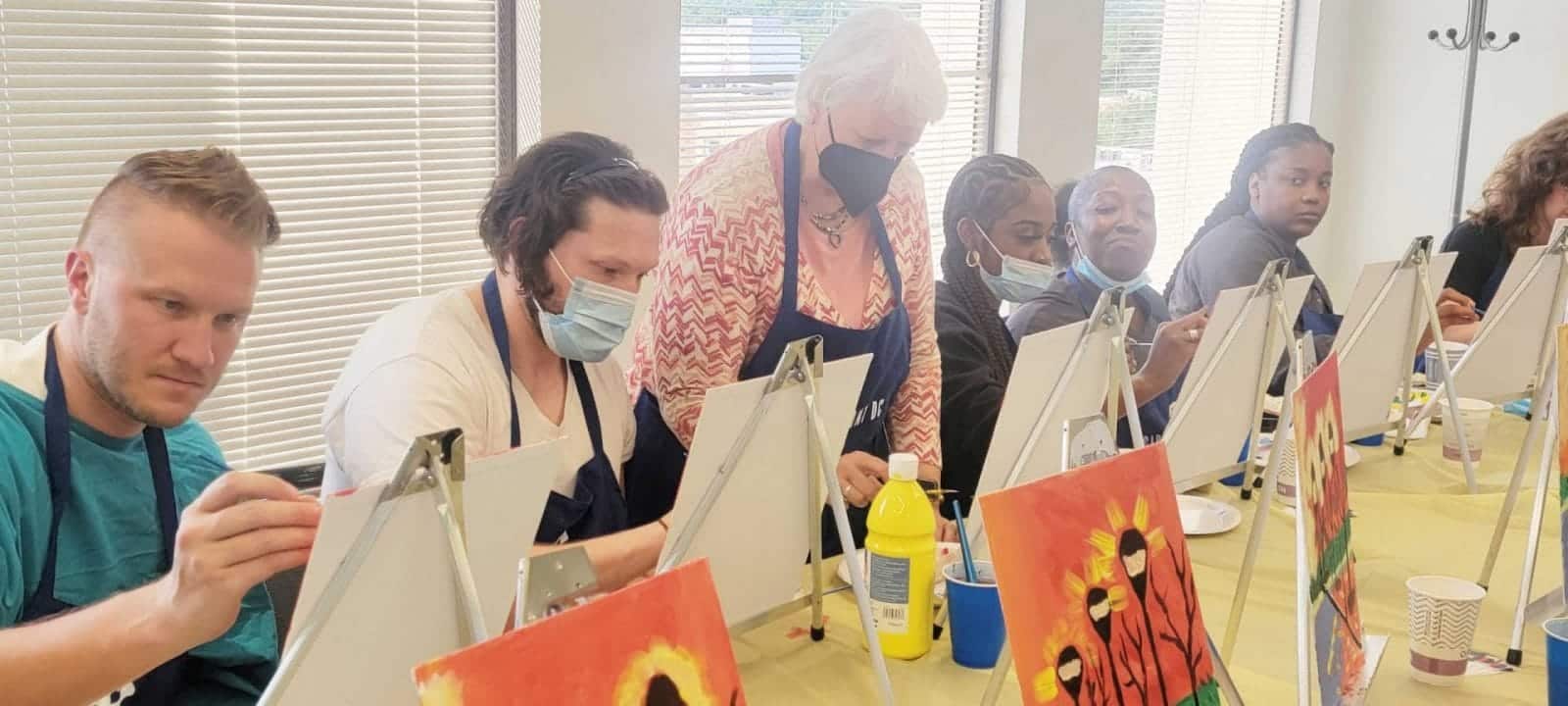 People enjoying a sip and paint session at a table.