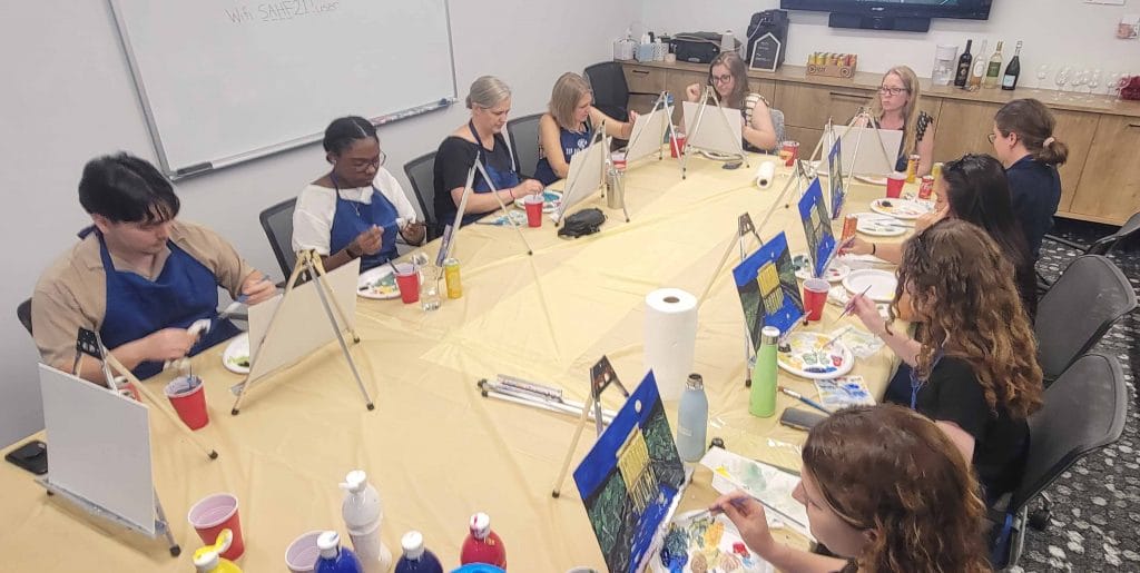 A group of people enjoying a dc sip and paint session at a restaurant table.