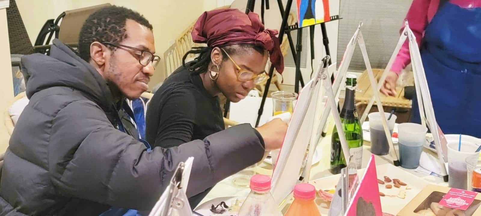 A group of people sipping and painting at a table in DC.