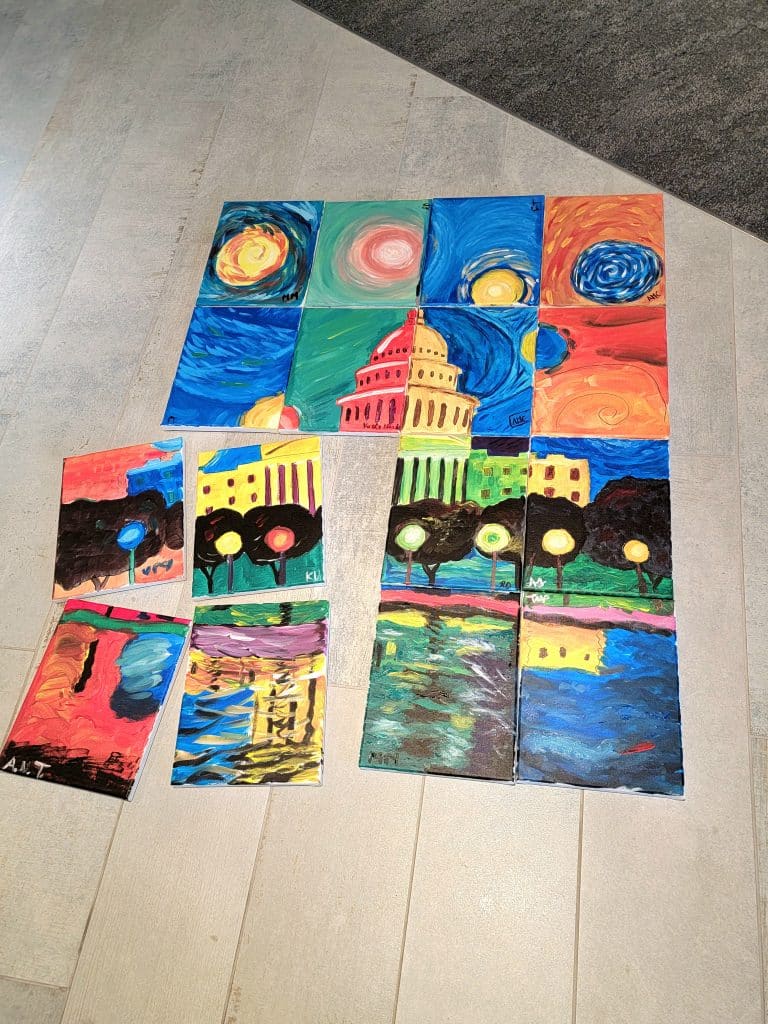 A collection of paintings arranged on a wooden floor in Sip and Paint DC depicts vibrant scenes, including a stylized building, swirling skies, and colorful reflections.