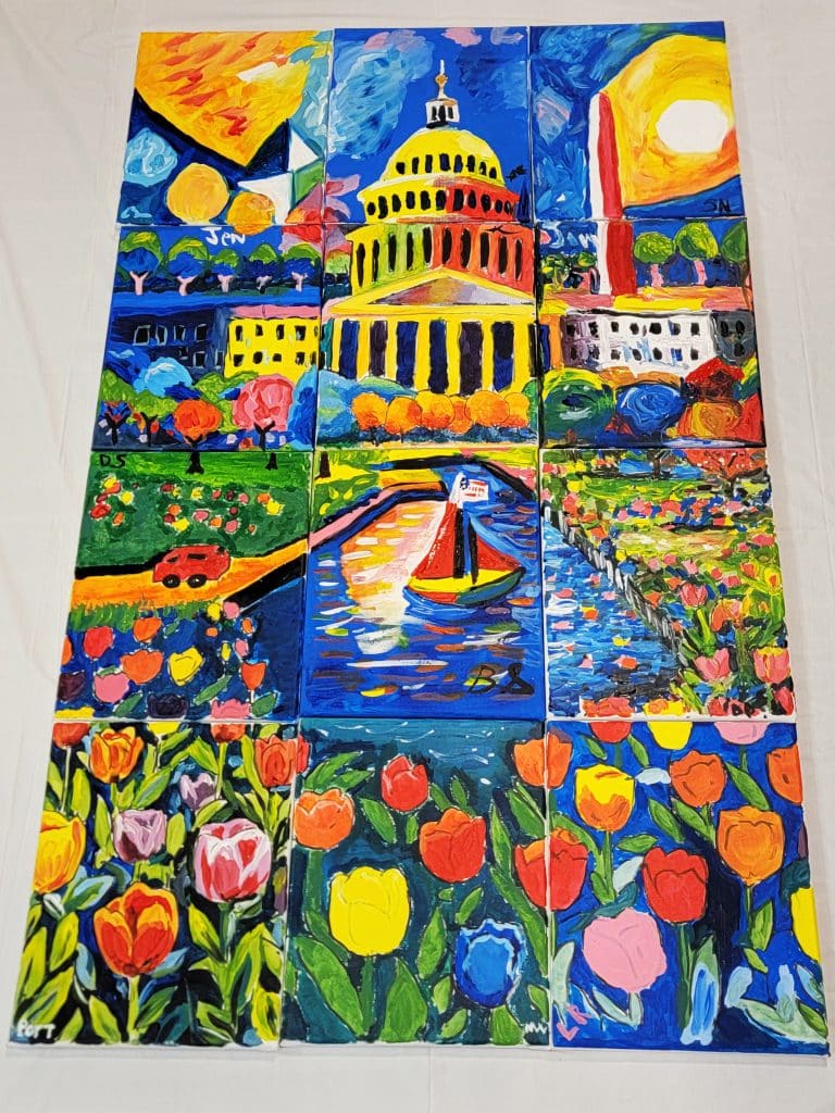 A colorful nine-panel painting depicts the U.S. Capitol, Washington Monument, a sailboat on water, tulip fields, and a red car, all in a vibrant, impressionistic style.