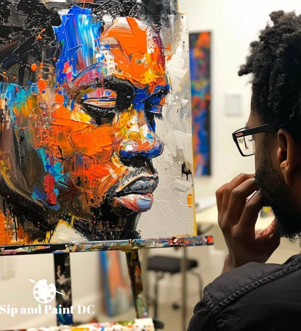 A man looking at a painting in an art studio.